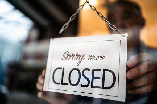 Business ower holding closed sign on storefront door