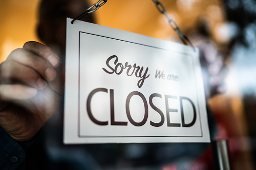 Business ower holding closed sign on storefront door