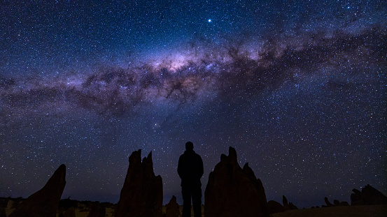 Man in the Pinnacles (Western Australia) looking up at the Milky Way as it slowly descends in the night's sky.