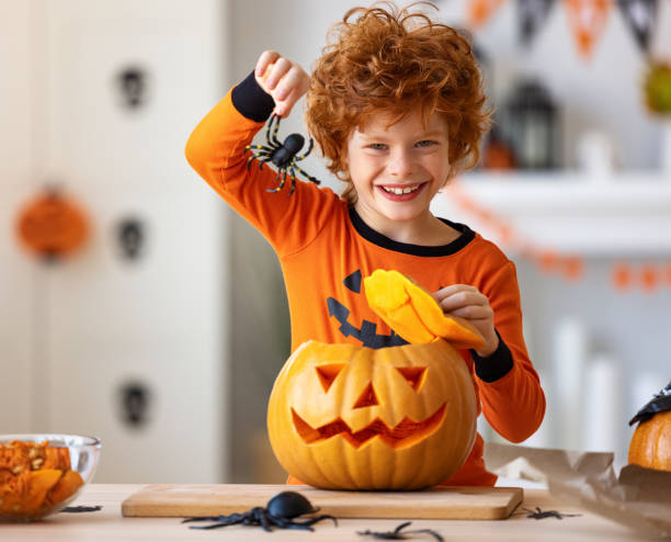istock Happy redheaded boy in  costume laughs and with  spider and pumpkin Jack o lantern   during a Halloween celebration 1275821040