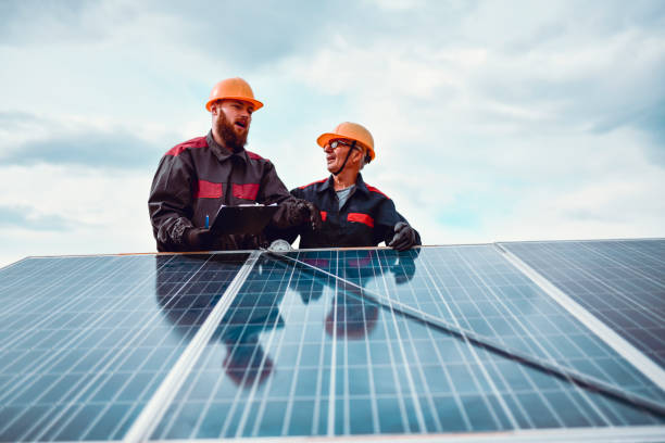 istock Senior And Junior Workers Measuring Solar Panel Length On House Roof 1275821869