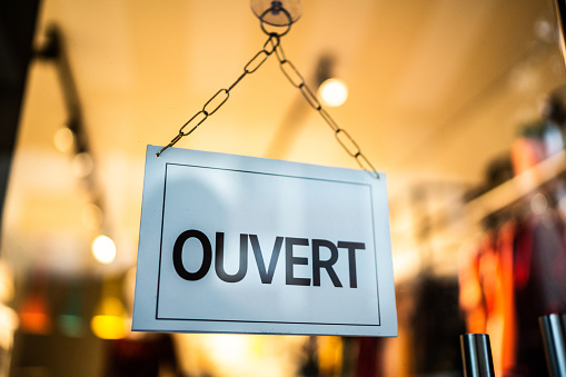 Opened sign (ouvert) seen through glass door at store