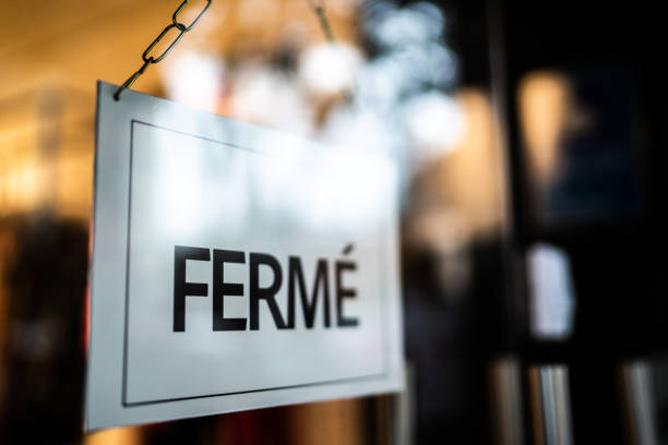 Closed sign (fermé) seen through glass by at store Closed sign (fermé) seen through glass door at store shut up stock pictures, royalty-free photos & images