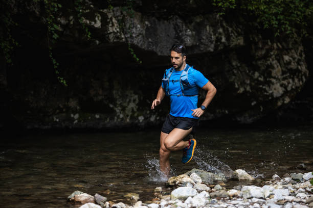 istock Young man running in mountain river 1275823411