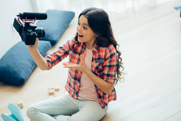 istock Enthusiastic teenager with modern camera at home 1275829712