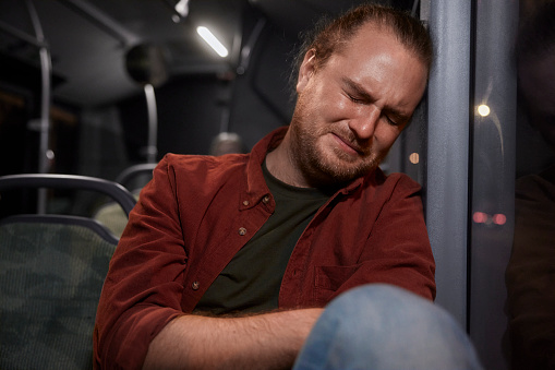 Sad caucasian man in tears sitting on public bus crying