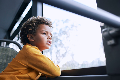 African-american young boy with afro hair looking out the window inside public bus