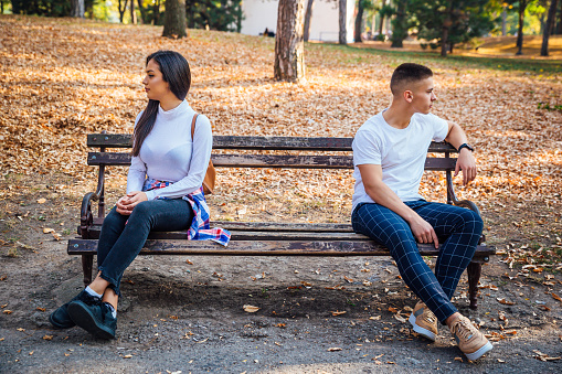 Young couple sitting in the park, having relationship problems