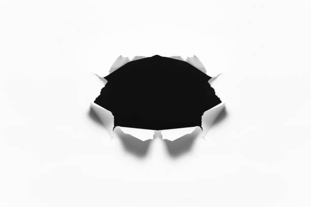 istock Torn black hole in the sheet of white paper. 1275834579