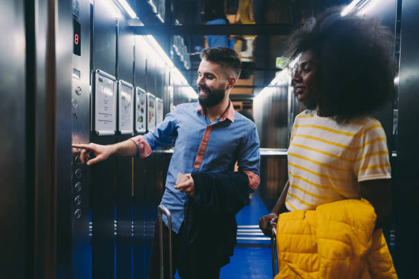 istock Couple in hotel entering elevator pushing floor button 1275840990