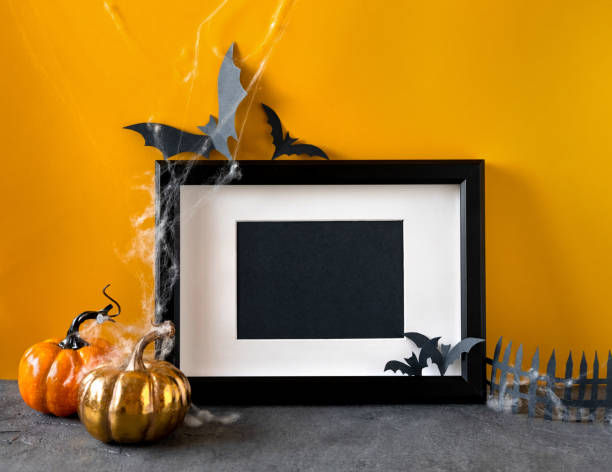 istock Happy Halloween holiday concept. Black frame on orange background. Halloween decorations, pumpkins, bats, black frame. Halloween party greeting card mockup with copy space. 1275841084