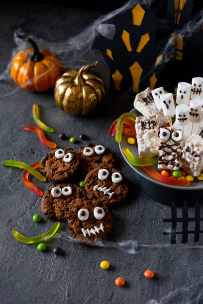 istock Modern Halloween background. Halloween candy bar: funny monsters made of biscuits with chocolate and ghosts marshmallow close-up on the table. Halloween party decoration. Trick or treat concept. 1275841122