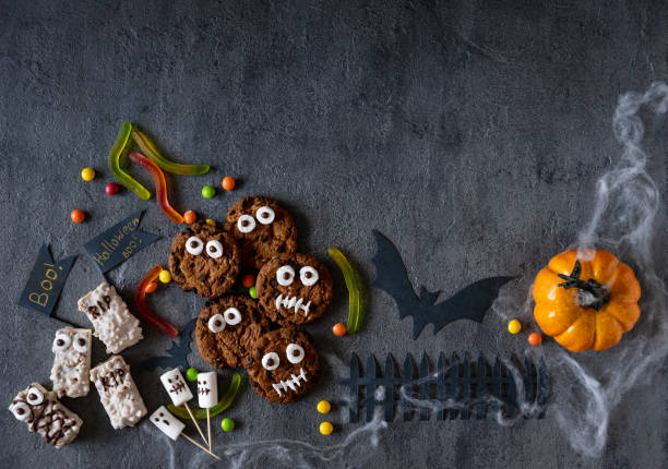 istock Modern Halloween background. Halloween candy bar: funny monsters made of biscuits with chocolate and ghosts marshmallow close-up on the table. Halloween party decoration. Trick or treat concept. 1275841146