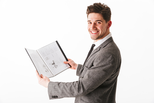 Portrait of a smiling young businessman showing an open textbook isolated over white background