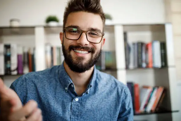 Smiling young man having online conference from home office