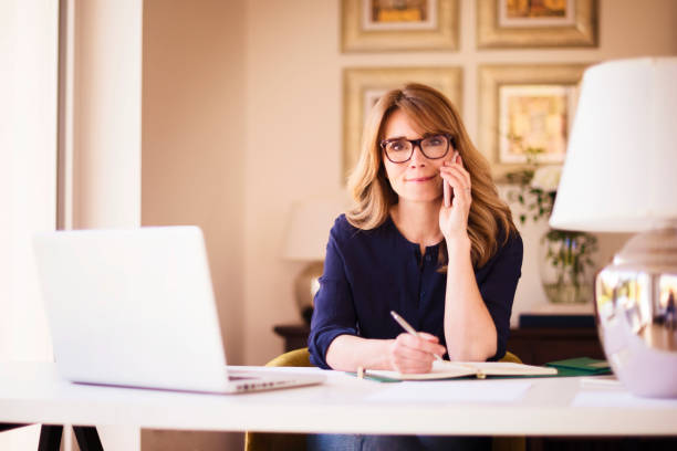 istock Attractive businesswoman working from home while using mobile phone and laptop 1275841620