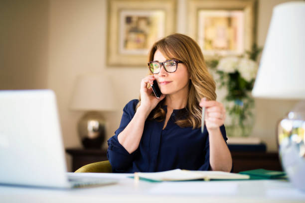 istock Businesswoman using laptop and mobile phone while working at desk 1275841624