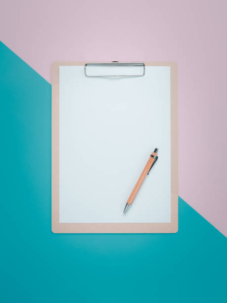 istock Blank clipboard with brown pen on pink and cyan background. 1275844164