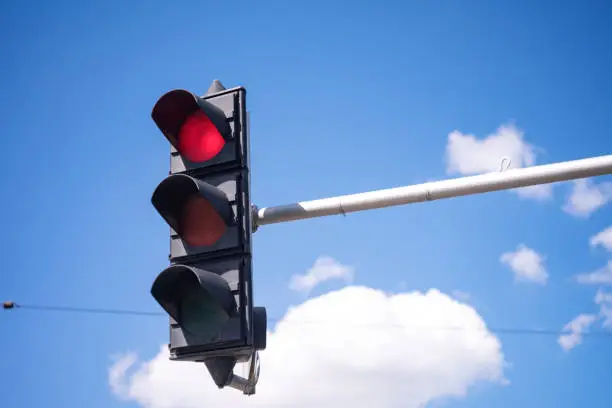 A close view of an old black traffic stoplight showing the red signal light.