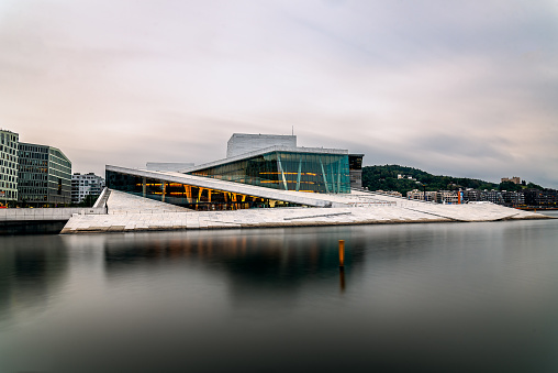 Oslo, Norway - August 10, 2019: Exterior view of Opera house in Oslo. Long exposure at dusk. New modern building designed by Snohetta architects. It is the National Theater of Opera and Ballet of Norway