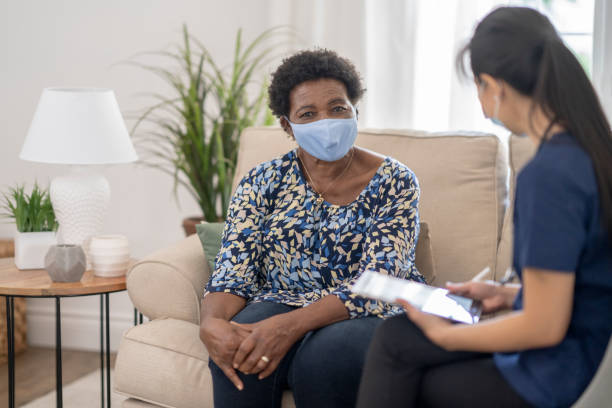 istock Home caregiver visiting with patient wearing masks 1275851191