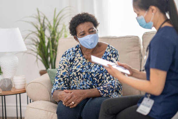istock Home caregiver visiting with patient wearing masks 1275851202