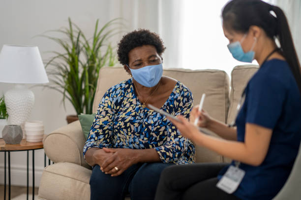istock Home caregiver visiting with patient wearing masks 1275851210