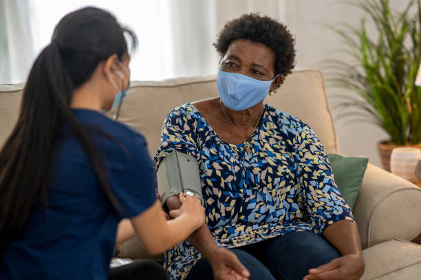 istock Home caregiver visiting with patient wearing masks 1275851215