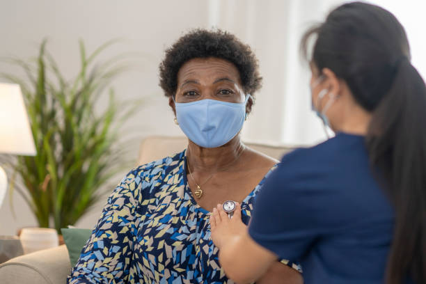 istock Home caregiver visiting with patient wearing masks 1275851217