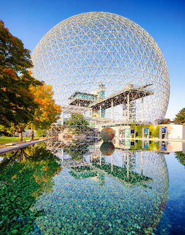 Montreal's biosphere environment museum with its reflection in pool in parc Jean-Drapeau, lit by an Autumn sunset. The structure was build for the expo67 universal exhibit and was initially used as the American pavillion.