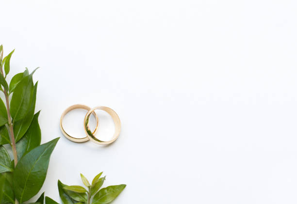 istock Two gold wedding rings and fresh green leaves 1275853882