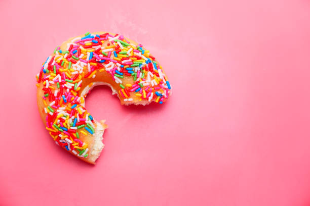 istock Close up of half eaten donut on pink background 1275855985