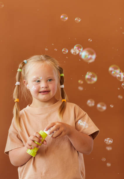 istock Happy Girl with Down Syndrome Blowing Bubbles 1275856606