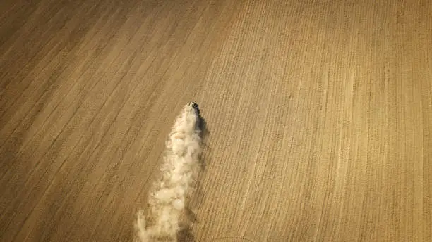 Photo of Tractor, harrow and dust on an agricultural field - aerial view