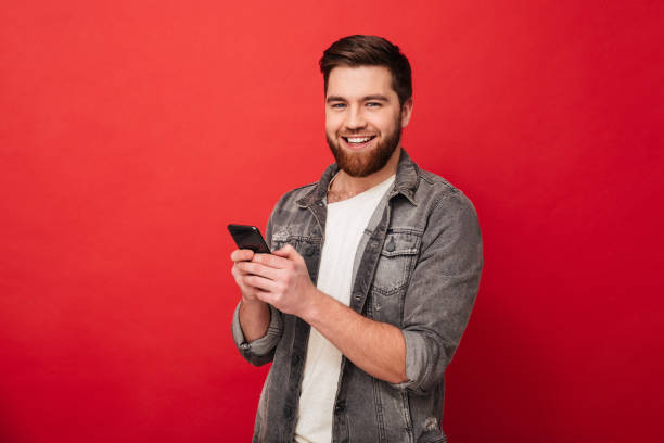 istock Smiling bearded man holding smartphone and looking at the camera 1275861775