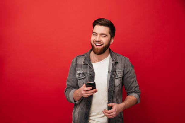 istock Image of Laughing bearded man holding smartphone and looking away 1275861818