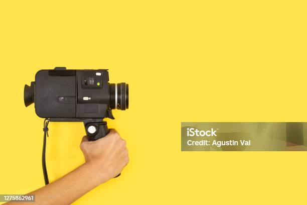 Woman Holding An Eight Mimlimiters Camera On A Yellow Background Stock Photo - Download Image Now