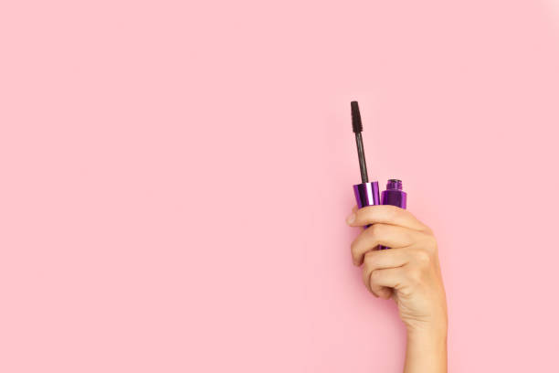 istock Woman hand holding an eyelash mascara on a pink background 1275863146