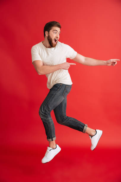 istock Emotional bearded man jumping pointing to copyspace. 1275864929