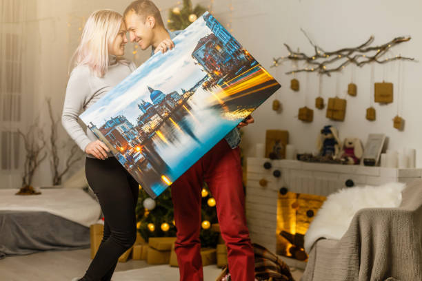 Happy young woman and her boyfriend holding canvas while moving into new home Happy young woman and her boyfriend holding canvas while moving into new home artists canvas photos stock pictures, royalty-free photos & images