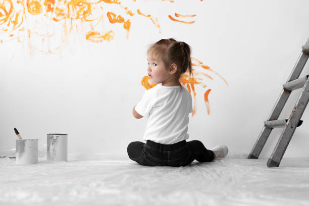 niña con un pincel en las manos se dibuja en la pared. concepto de renovación del hogar. - una sola niña fotos fotografías e imágenes de stock