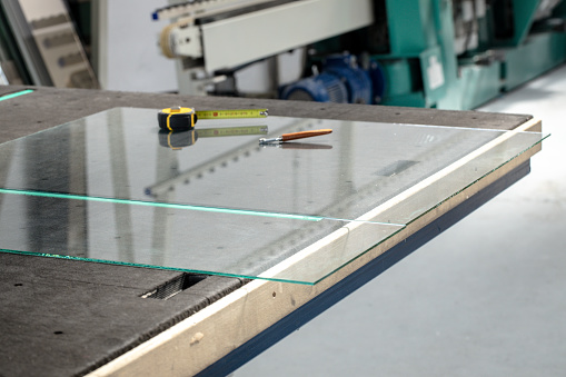 The glass pane and the cutting tools lying on a professional glass table / factory