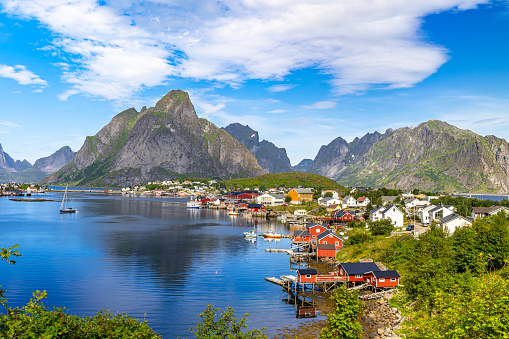 This image shows famous fishing Reine Village, Lofoten Islands, Norway. Ocean and wooden houses and mountain can be seen in the image.