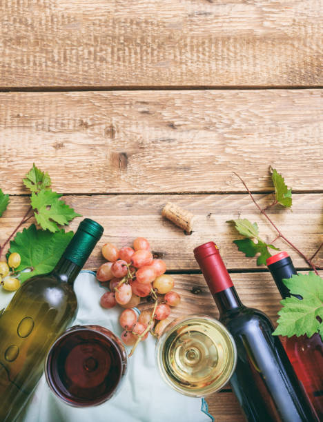 istock Red and white wine glasses and bottles on wooden background 1275868499