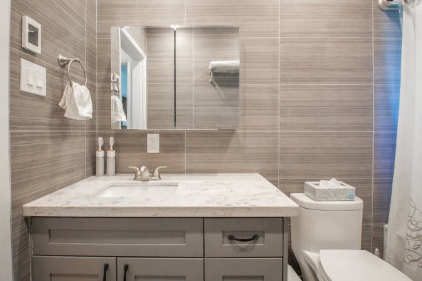A Small Fancy Bathroom A cozy grey and white bathroom with a big mirror with floor to ceiling tiling medicine cabinet stock pictures, royalty-free photos & images