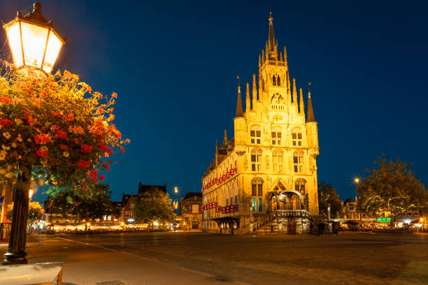 Famous city hall of Gouda is illuminated at night Gouda, Netherlands - September 2020: City hall in gothic style on the market square in the old town of Gouda, Holland is illuminated at night. Selective focus. gouda south holland stock pictures, royalty-free photos & images