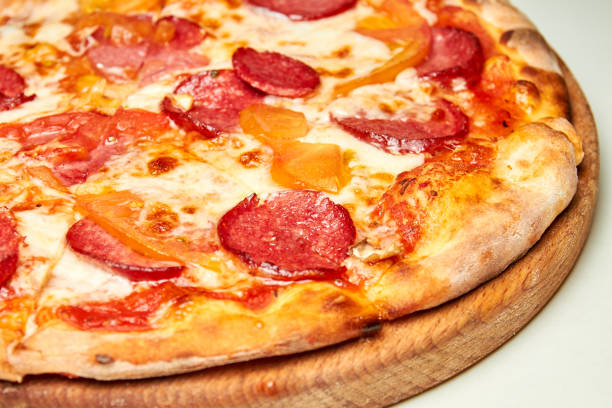 istock Pizza with salami, bell pepper, tomatoes and cheese on a light background. Close-up, selective focus 1275874916