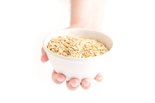 Front view of a oat flakes bowl held by a woman's hand on a white background