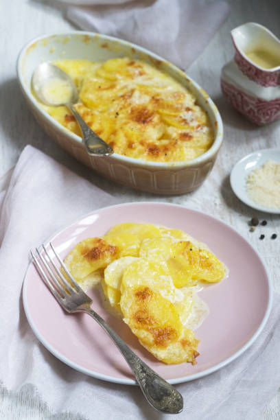 francuskie danie gratin dauphinois w formie ceramicznej na jasnym tle. rustykalny styl. - dauphinois zdjęcia i obrazy z banku zdjęć