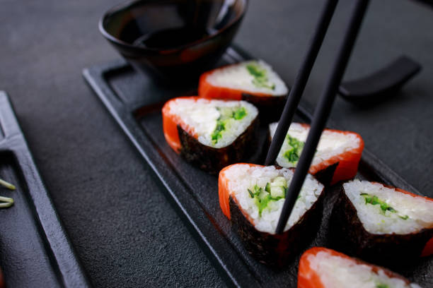 istock Chopsticks taking salmon maki roll from plate 1275876177